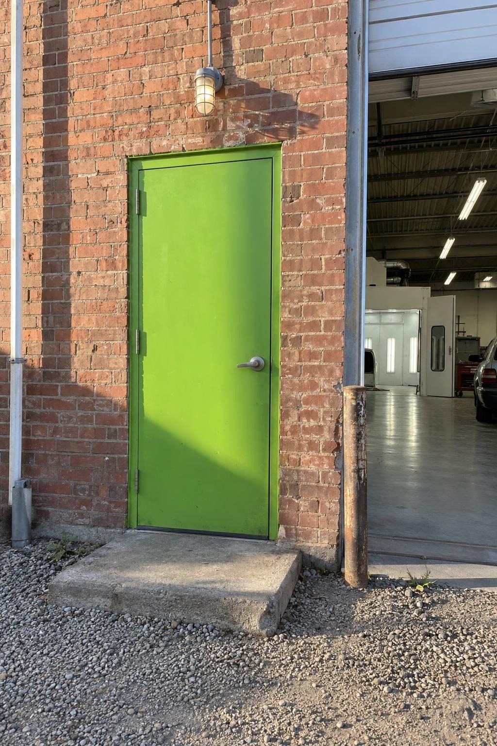 Narrow lime-green steel door in the shop's red-brick wall