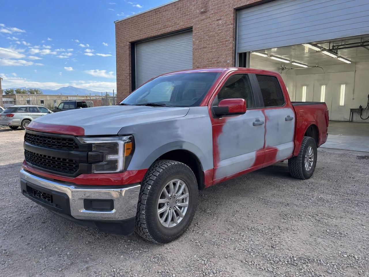 Red pickup with grey primer patches on the hood, fender and doors